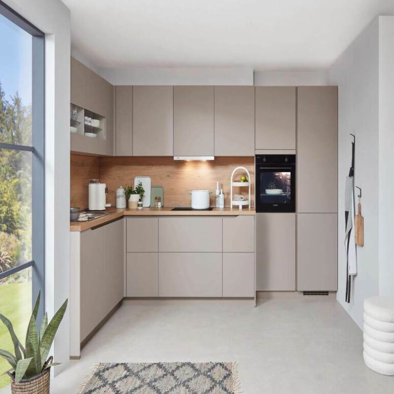 Musterküche in Kaschmir als L-Küche mit Holzrückwand und Backofen im Hochschrank – Küchenstudio Mannheim